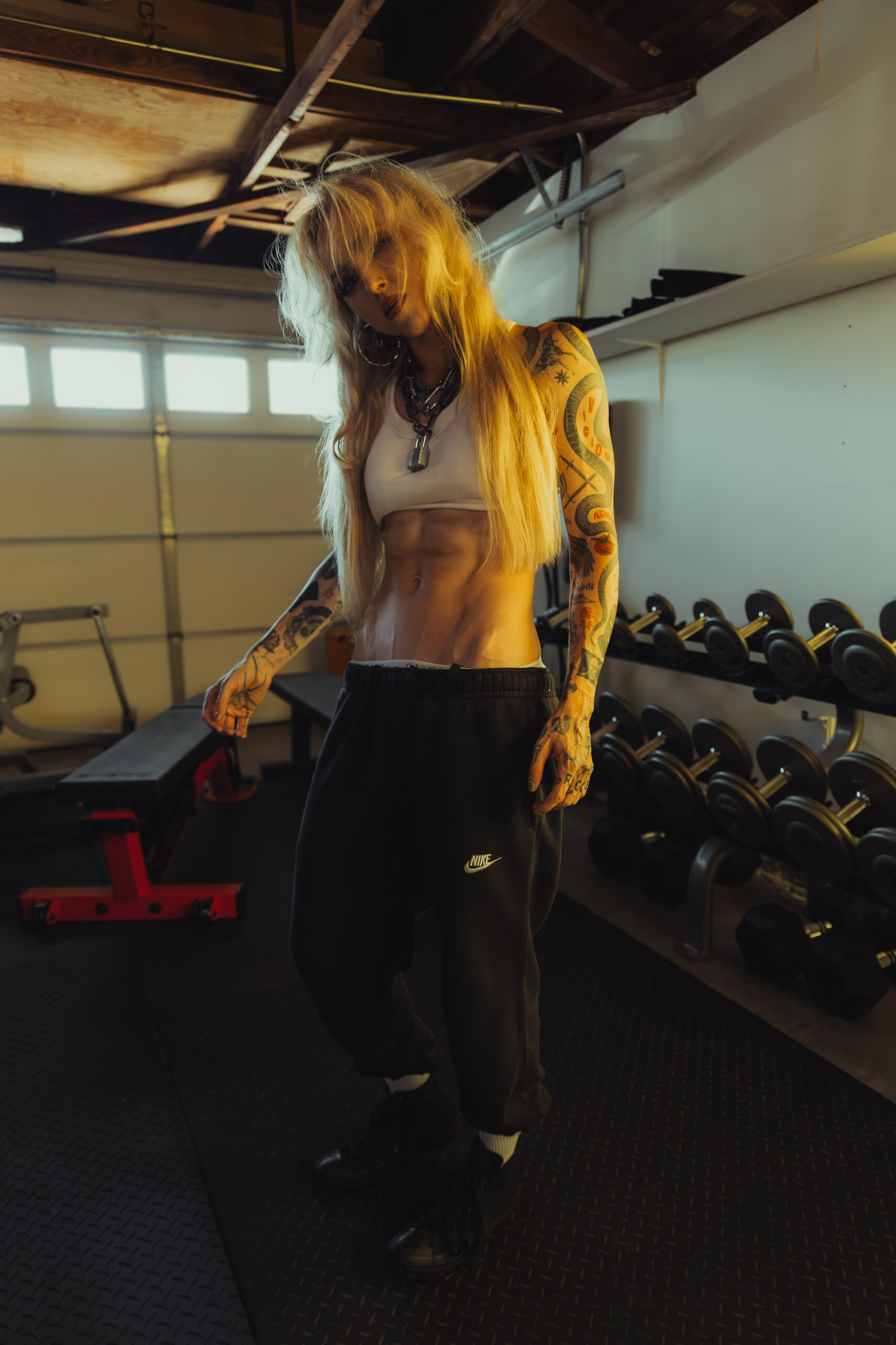 Female fitness coach with visible abdominal definition in a private gym, representing precision-based body recomposition coaching.